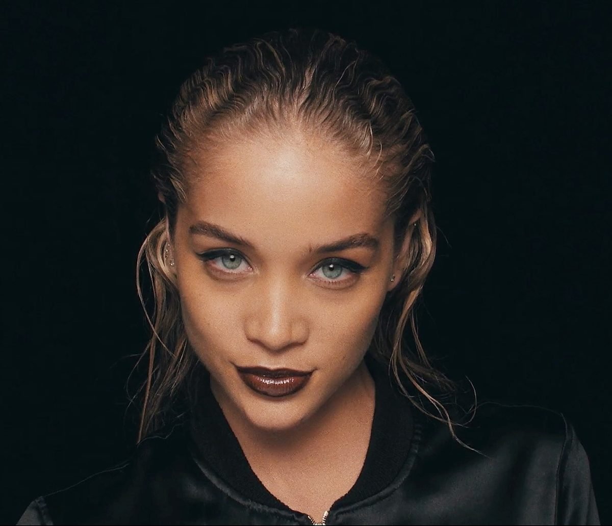 Woman with slicked-back hair and dark lipstick against a black backdrop, showing studio lighting for headshots.