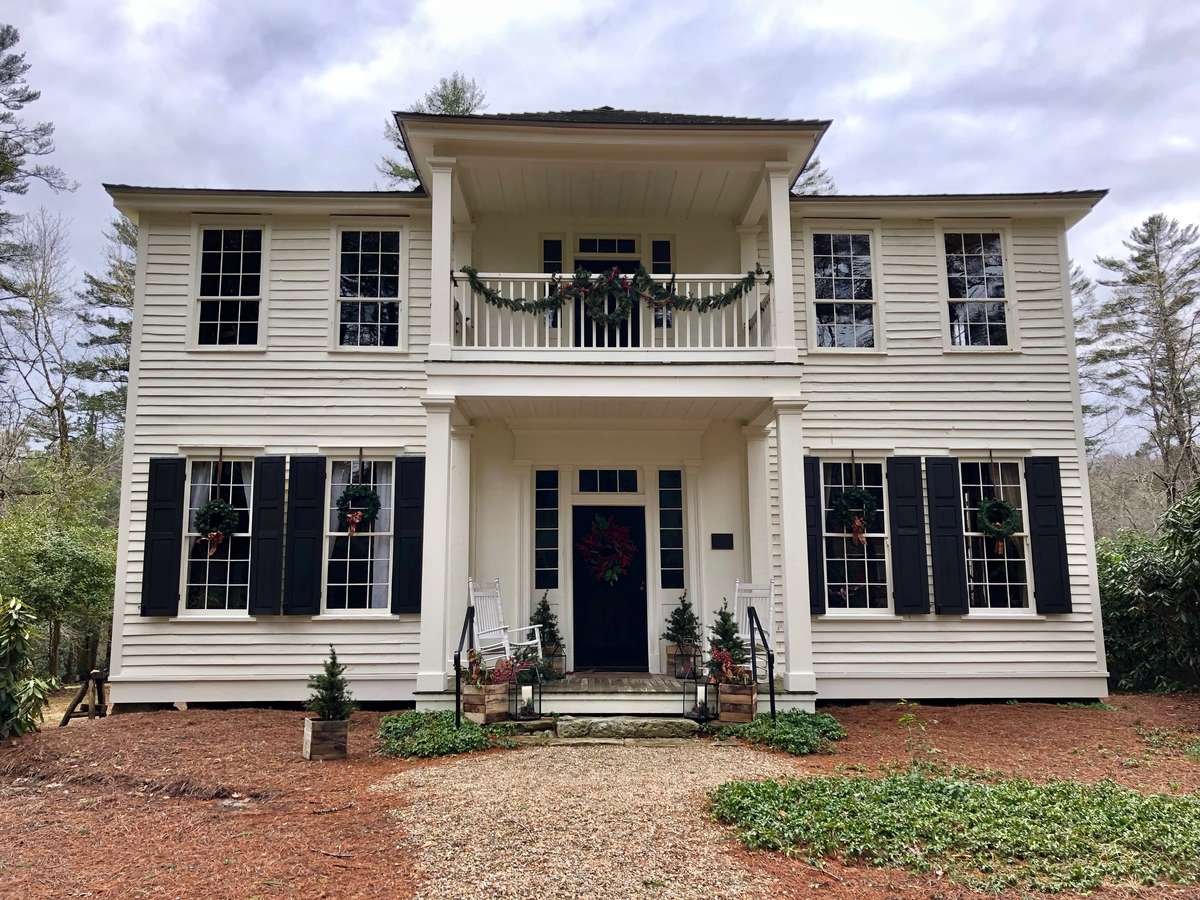 White colonial house facade: symmetry and patterns photography of repeating shuttered windows and central porch.